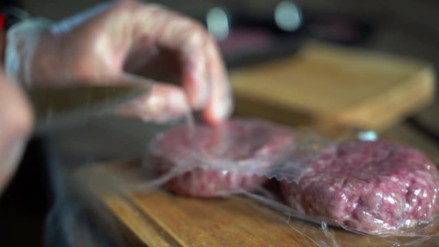 Raw meat burgers in food pellicle. A brazier grill outdoors