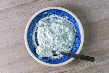 dinner sauce: sour cream and onions in a bright porcelain plate on a wooden table