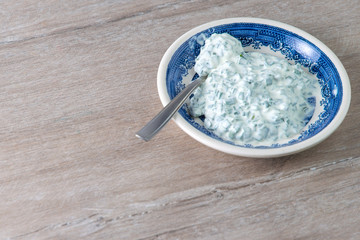 dinner sauce: sour cream and onions in a bright porcelain plate on a wooden table
