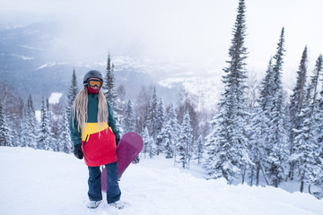 Female snowboarder with snowboard in the mountains on a snowy slope.