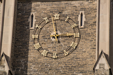 Golden clock on the wall of old gothic tower