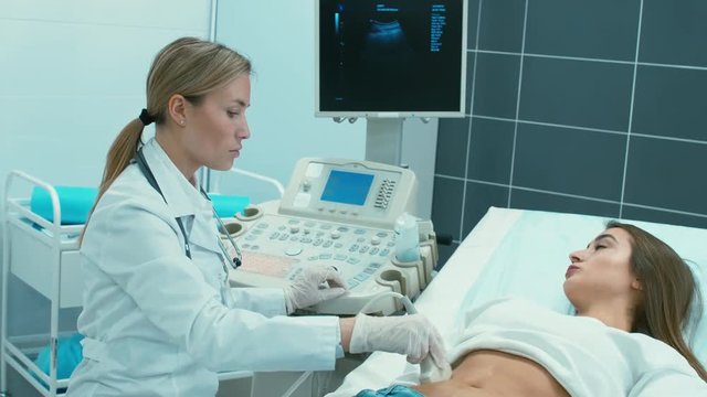 Young Caucasian doctor making ultrasonography for pregnant patient