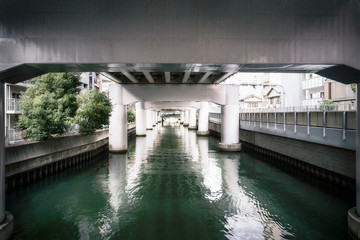 Perspective view with beautiful daytime filtered light at the River Canal under Hanshin Expressway Number 1, Namba, in downtown Osaka, Japan.