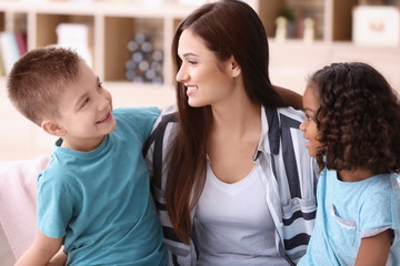 Young woman with little kids indoors. Child adoption