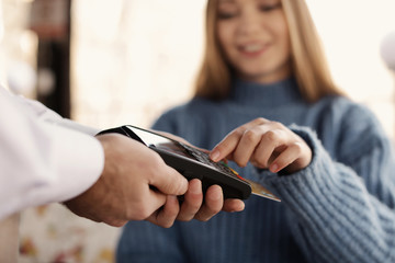Obraz na płótnie Canvas Woman with credit card using payment terminal at restaurant, closeup