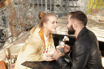 Lovely young couple enjoying tasty coffee at table outdoors