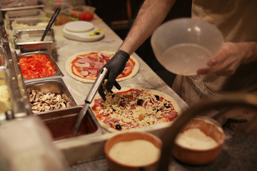Man making pizzas at table, closeup view