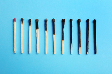 Row of burnt matches and whole one on color background, flat lay. Human life phases concept