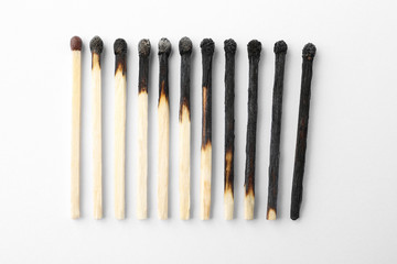 Row of burnt matches and whole one on white background, top view. Human life phases concept