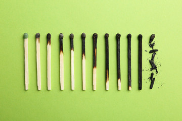 Row of burnt matches and whole one on color background, flat lay. Human life phases concept