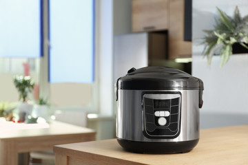 Modern multi cooker on table in kitchen. Space for text