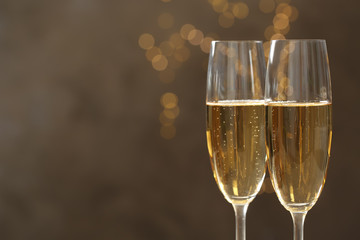 Glasses of champagne against blurred lights, closeup. Space for text