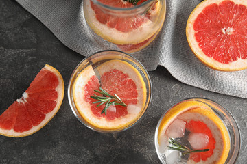 Glasses of infused water with grapefruit slices on grey table, flat lay