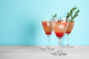 Glasses of grapefruit cocktails on table against color background. Space for text