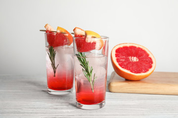 Glasses of cocktail and grapefruit half on table