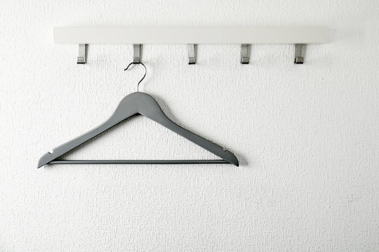 Rack with empty clothes hanger on light wall. Wardrobe accessory