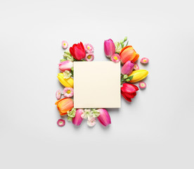 Beautiful composition with spring flowers and blank card on white background, top view. Space for text