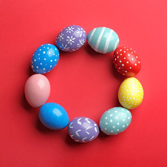 Frame made of painted Easter eggs on color background, top view. Space for text