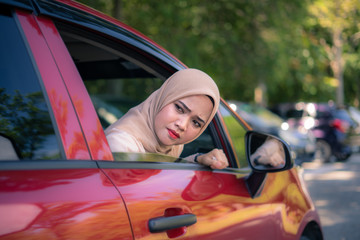 Portrait of young Muslim woman driving a car with face expressions, female drivers concept.