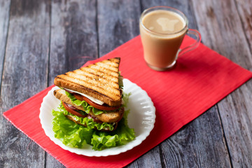 Sandwich with cheese, tomato, cucumber, sausage and salad on wooden background. Coffee with milk Horizontal orientation