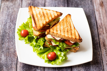 Sandwich with cheese, tomato, cucumber, sausage and salad on wooden background. Horizontal orientation