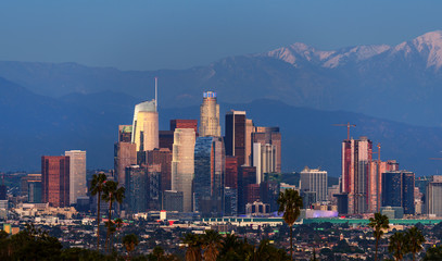 Downtown Los Angeles skyline with snow capped mountains behind at twilight