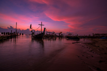 Fototapeta premium The blurred background of the morning twilight by the sea, changing the color of the beautiful sky, there is a fishing boat docked waiting to go out to find fish again.