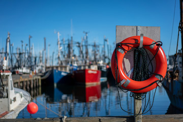 Bright orange life buoy on dock at commercial fishing harbor dock