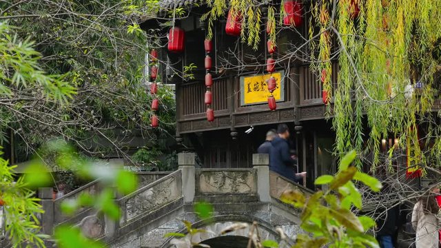 Chengdu Sichuan/China-January 15 2019: time lapse of tourist walking on the stone bridge in Jin li street , with traditional Chinese wooden house and red lantern in the background