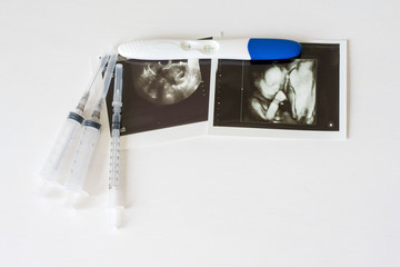 Ultrasound scan of baby and pregnancy test on white background