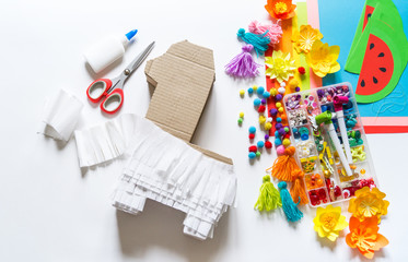 Diy cinco de mayo Mexican Pinata llama made cardboard and crepe paper your own hands on a white background.