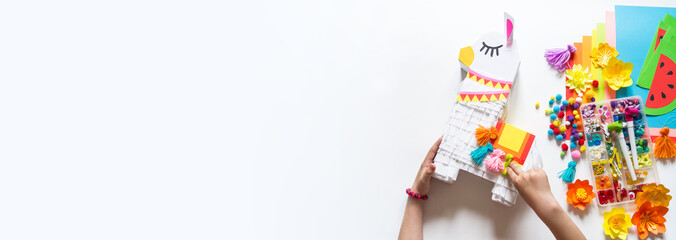 Diy cinco de mayo Mexican Pinata llama made cardboard and crepe paper your own hands on white background. Copy space © Дарья Колпакова