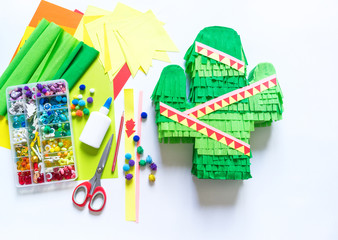 Diy cinco de mayo Mexican Pinata cactus made cardboard and crepe paper your own hands on a white background.