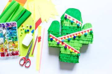 Diy cinco de mayo Mexican Pinata cactus made cardboard and crepe paper your own hands on a white...