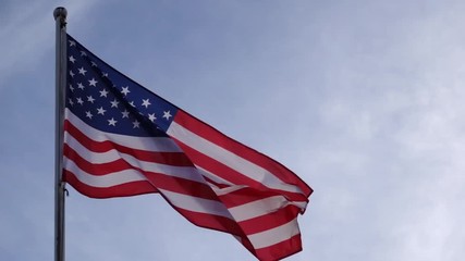 United States flag waving in the wind with clear blue sky and slow motion