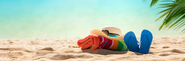 Keuken spatwand met foto Beach accessories straw hat, flip flops, towel on  sunny tropical Caribbean beach with palm trees and turquoise water, caribbean island vacation, hot summer day © Mariusz Blach