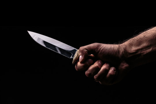 Hunting knife in hand on dark background