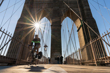 Scene of stop motion bicycle with Brooklyn bridge when sunrise, USA downtown skyline, Architecture and building with tourist concept