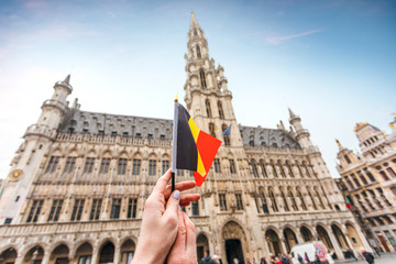 Woman tourist holds in her hand a flag of Belgium against the background of the Grand-Place Square...