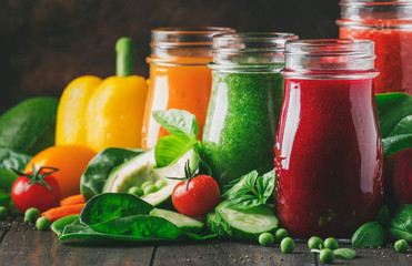 Colorful vegetable juices and smoothies from tomato, carrot, pepper, cabbage, spinach, beetroot in bottles on kitchen table, vegan food and drink, selective focus