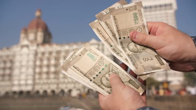 A man considers Indian 500 rupees on Mumbai street. Hands close up.