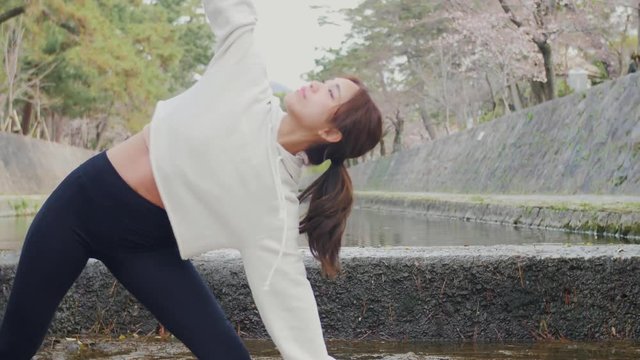 Japanese women doing yoga on Cherry blossom river.