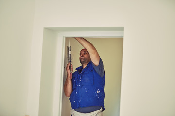 Worker using silicone for walls and door frame inside the house - renovation fixes.