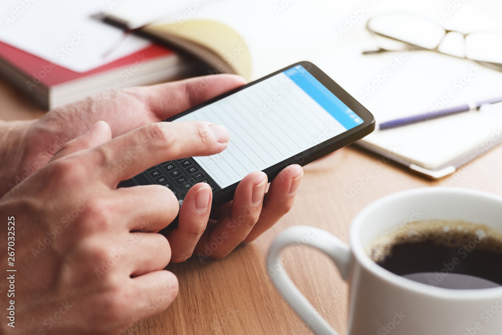 Poster closeup of male hands touching smartphone screen at table. smartphone user writing memo.