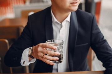 Handsome man in a black suit. Businessman working in a cafe