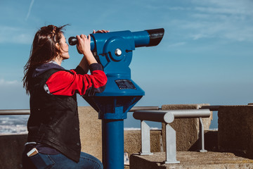 Woman looking at the city of Barcelona from Tibidabo, using a coin operated pair of binoculars.