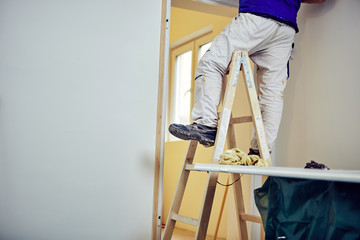 Worker using silicone for walls and door frame inside the house - renovation fixes.