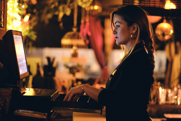 Concepto pequeño negocio o emprendimiento personal: una joven camarera en la máquina registradora...