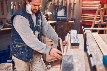 Male carpenter working on old wood in a retro vintage workshop.