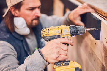 Male carpenter working on old wood in a retro vintage workshop.